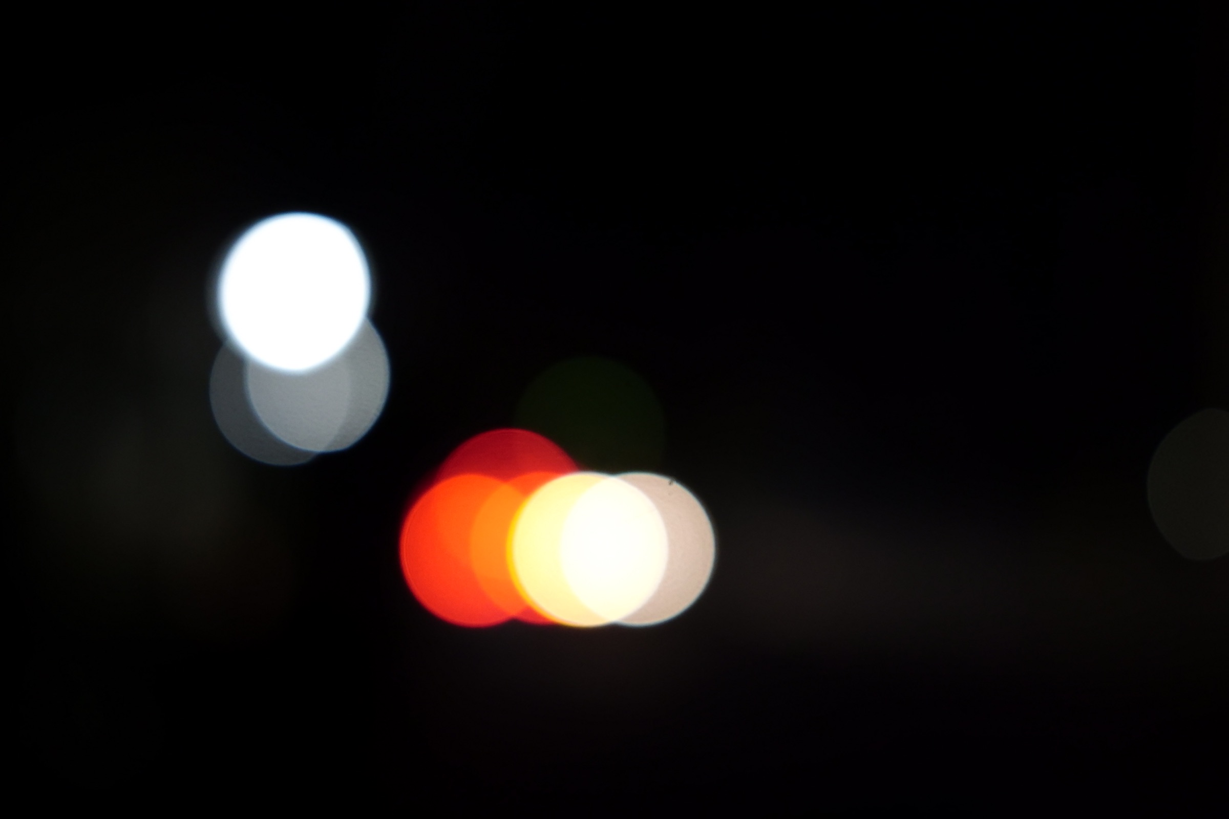 暗闇に白や赤、オレンジの光が丸くぼけて浮かぶ写真